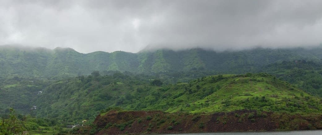 Green hills with a flat band of cloud resting along the ridgeline.