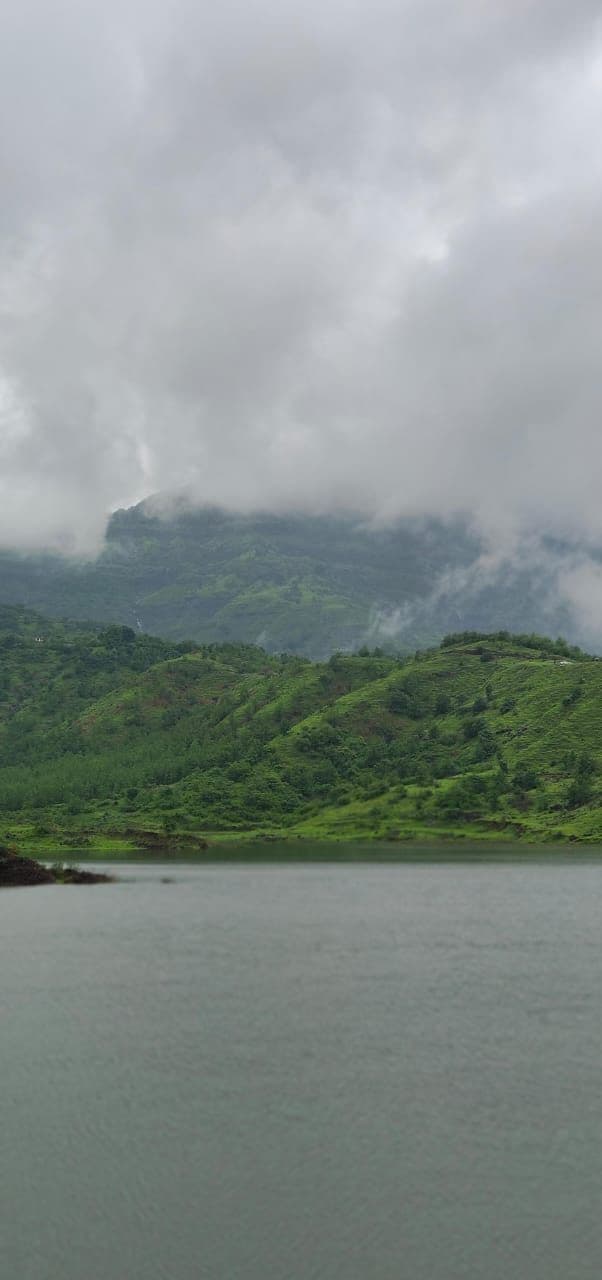 Mist drifting across a cliff face above a wide grey reservoir.